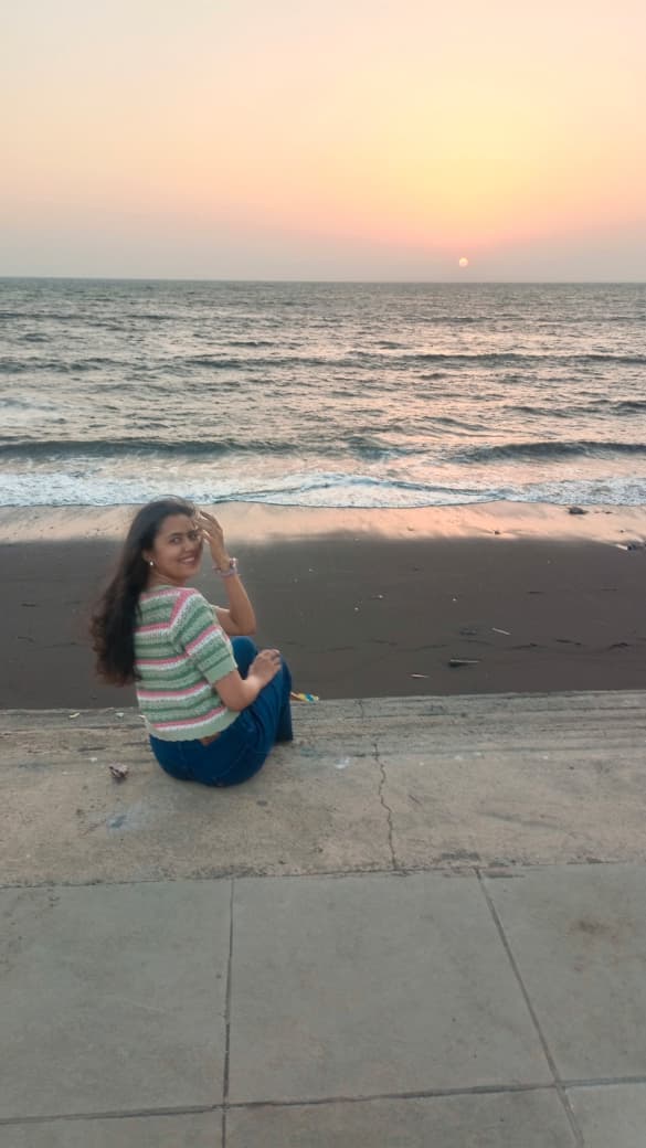 Riya sitting on the beach at sunset