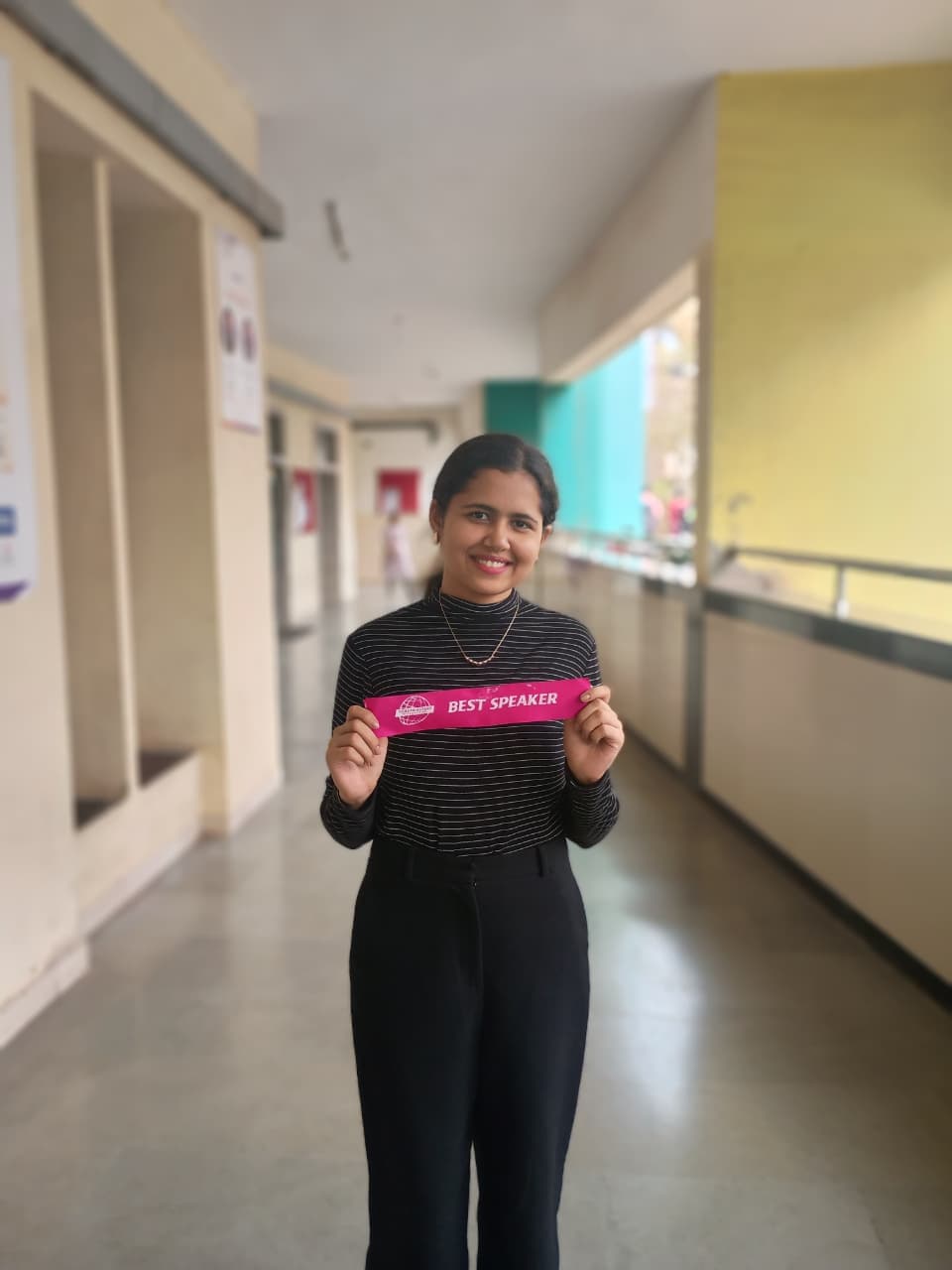 Riya holding a Best Speaker ribbon